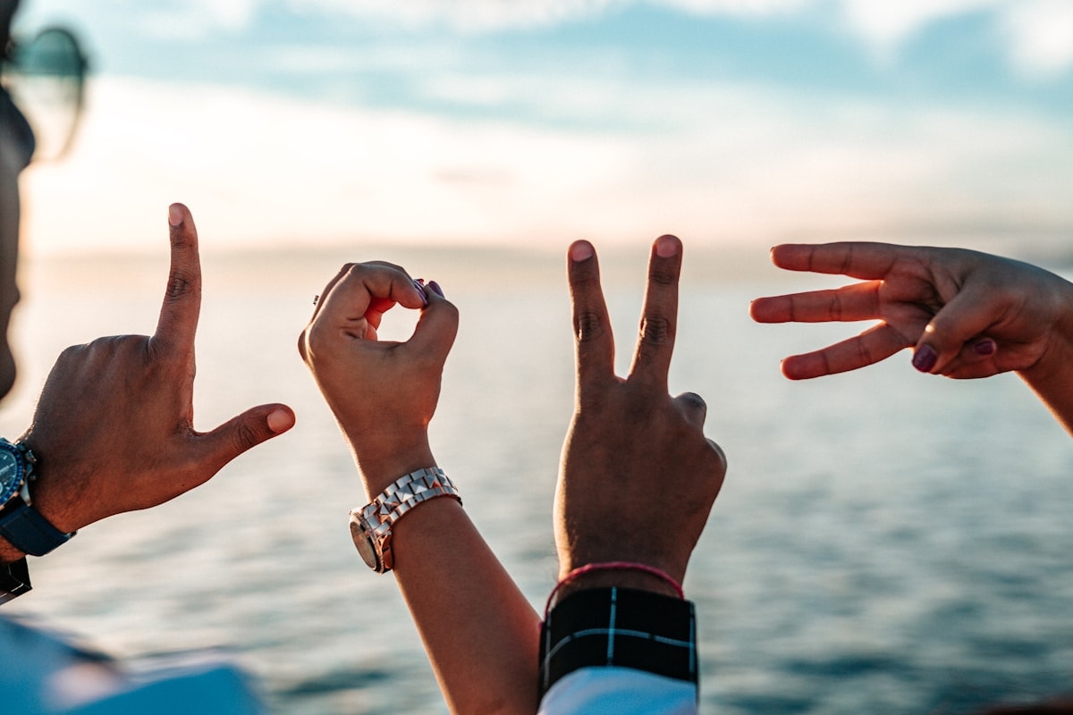 Friends making hand gestures at the beach